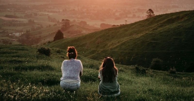 two women looking at townscape from pasture